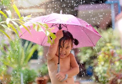 Cute girl enjoying rain with umbrella