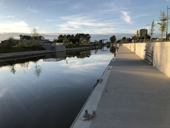 Footpath by lake against sky