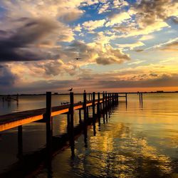 Pier on sea against cloudy sky