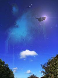 Low angle view of trees against blue sky