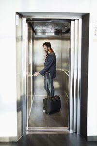 Businessman pushing button in elevator at hotel