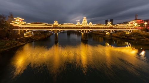 Illuminated bridge over river at night