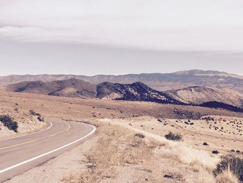 Scenic view of road by mountains against sky