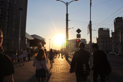 People walking on street in city at sunset
