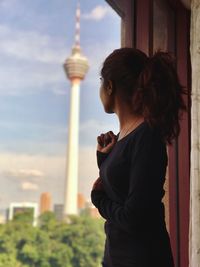 Woman looking at communications tower in city