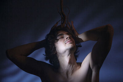 Portrait of young man looking away against gray background