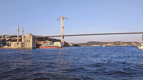 Suspension bridge over sea against clear sky