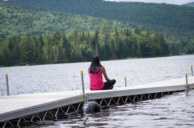 Woman sitting on pier over lake