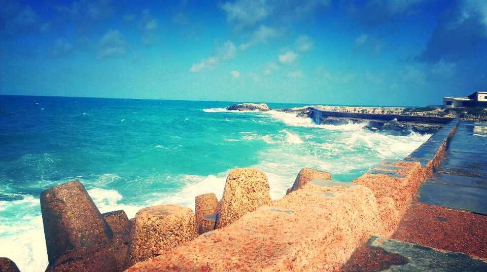 sea, horizon over water, water, beach, sky, blue, scenics, beauty in nature, tranquil scene, tranquility, shore, nature, rock - object, idyllic, cloud - sky, day, outdoors, wave, coastline, sunlight