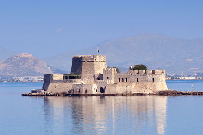 Historic building by sea against blue sky