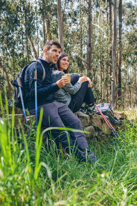 Man drinking water from while sitting on grass in forest