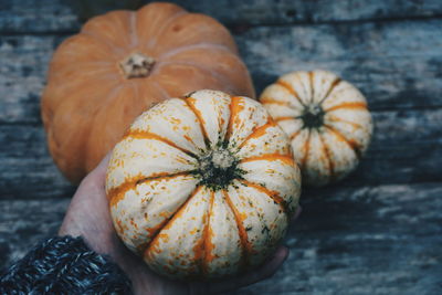 Cropped image of person holding pumpkin over table