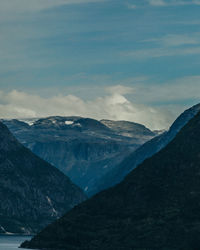 Layered mountain range and river under a cloudy sky