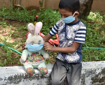 Asian boy wear mask and wearing mask to his doll to protect from corona virus