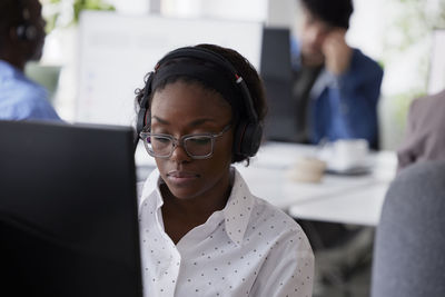 Mid adult woman using headset while sitting in office