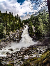 Scenic view of waterfall in forest against sky