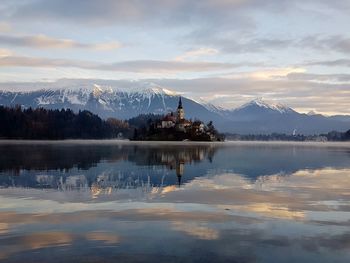 Scenic view of lake by snowcapped mountains against sky