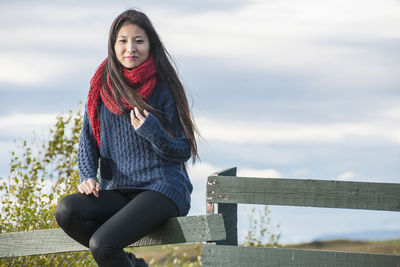 Beautiful woman sitting on a fence at the lake myvatn area