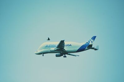 Low angle view of airplane flying against clear blue sky