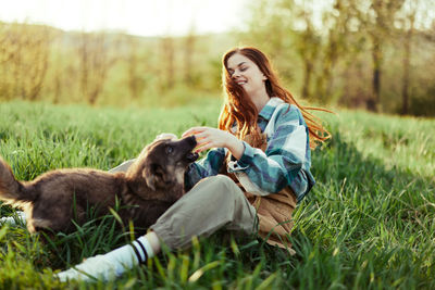 Smiling young woman with dog lying on grass