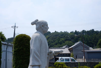 Statue by building against clear sky
