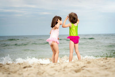 Rear view of siblings standing at beach