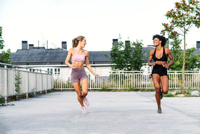 Sportive multiethnic females in activewear competing with each other while running fast together during training