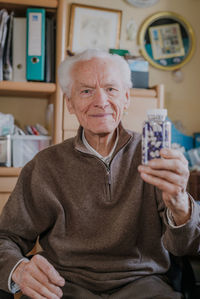 Smiling man holding medicines in bottle