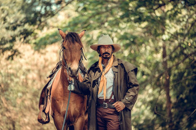 Man standing by horse in forest