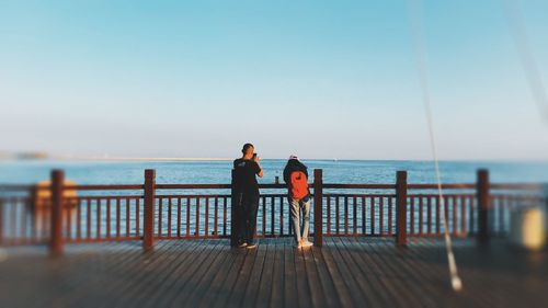 Rear view of people looking at sea against clear sky