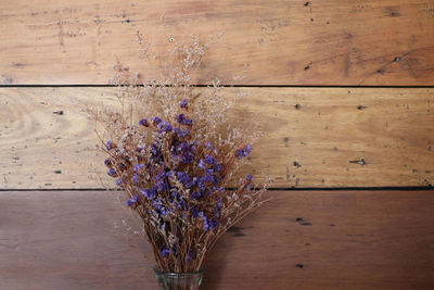 Purple flowering plants in vase on wooden table