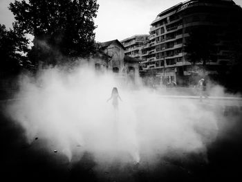 Silhouette man standing on street against buildings in city