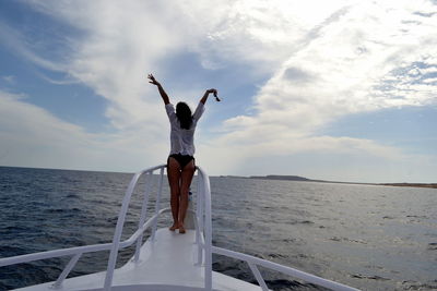 Rear view of woman standing on boat deck against sky