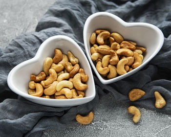 Tasty cashew nuts in bowls on a grey concrete background