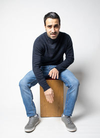 Portrait of young man sitting against white background