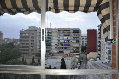 Buildings against sky seen through glass window