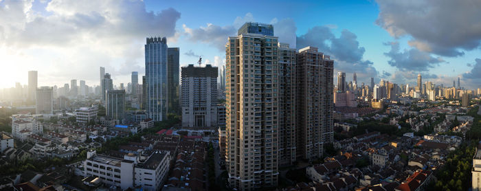 Aerial view of buildings in city against cloudy sky