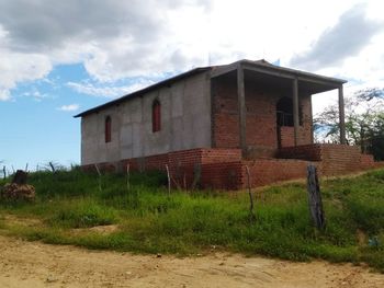 Abandoned house on field against sky