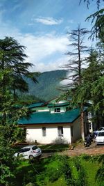 Houses by trees and buildings against sky