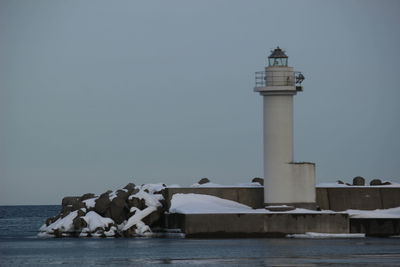 Lighthouse by sea against sky