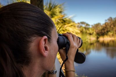 Close-up of woman looking lake through binoculars