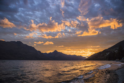 Scenic view of mountains against cloudy sky at sunset