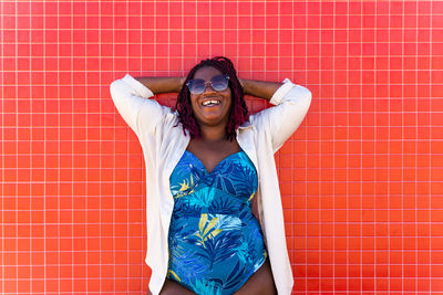 Portrait of young woman standing against wall