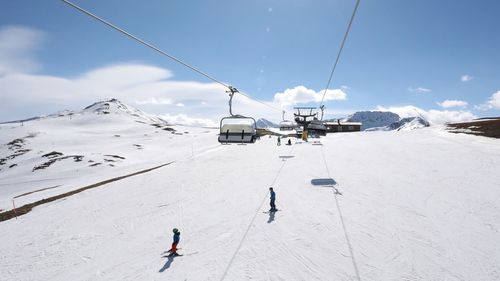 Ski lift over snowcapped mountains against sky