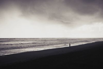 Silhouette person on beach against sky