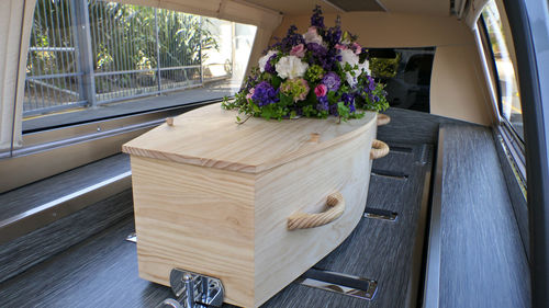 Closeup shot of a funeral casket or coffin in a hearse or chapel or burial at cemetery
