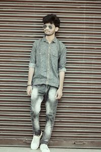 Portrait of young man standing against wall