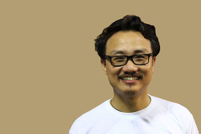 Portrait of young man wearing eyeglasses against gray background