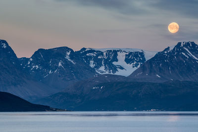 Scenic view of lake and snowcapped mountains against sky at dusk