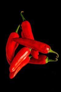 Close-up of red chili peppers against black background